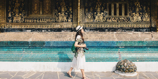 Student with a camera visiting Wat Xieng Thong, an iconic temple in Luang Prabang, the UNESCO world heritage town in north central of Laos.