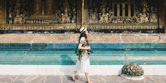 Student with a camera visiting Wat Xieng Thong, an iconic temple in Luang Prabang, the UNESCO world heritage town in north central of Laos.