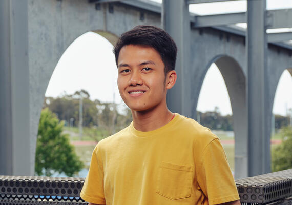 Deakin Malaysian international student alumni Voon standing and smiling on campus.