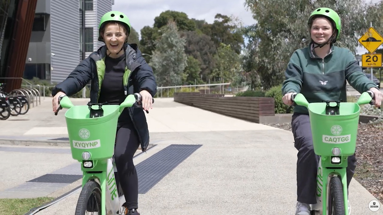 Two students riding Lime e-bikes