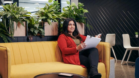 A Deakin master of communication students sits on a couch.