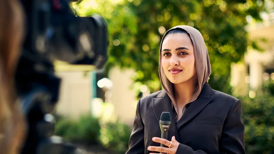 A Deakin master of communication student outside reporting, talking to camera.