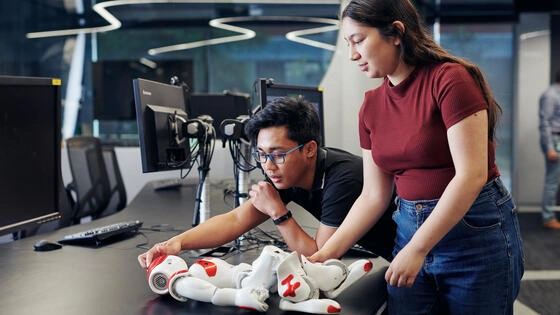 Two Deakin master of applied artificial intelligence students work together on a robot in a campus lab.