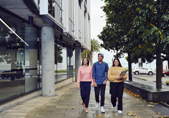 Three students walk outside on the street at the Geelong Waterfront Campus.