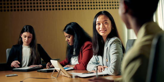 A group of Deakin business students at a desk.