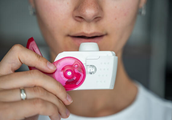 Person holding an asthma inhaler in their hand