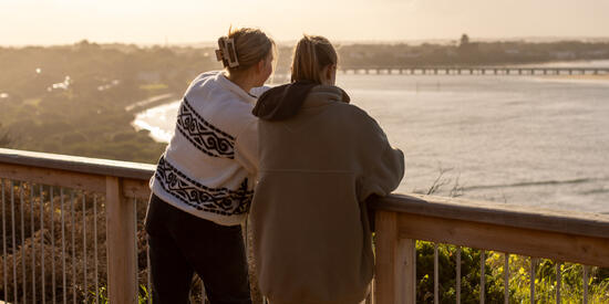 Two people stand at a lookout and gaze at the ocean in Barwon Heads.