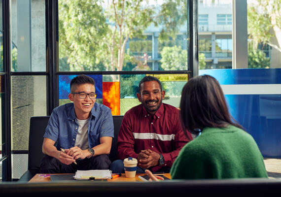 Three students sit and socialise on Deakin Waurn Ponds Campus.