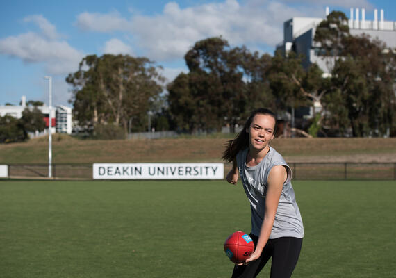 A woman playing football on an oval.
