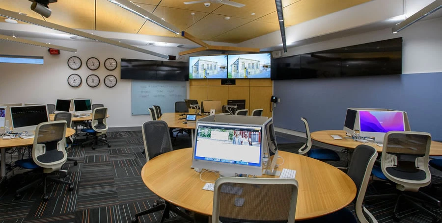 Inside the Newsroom and creative lab – showing seven large screens, world clocks on wall, and some of the workstation hubs