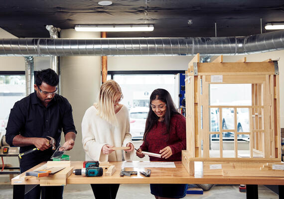 Three architecture students working with a model house