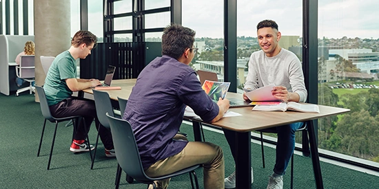 Deakin students collaborating at tables on campus.