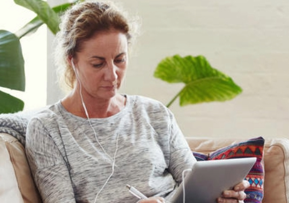 Deakin student studying online at home on their ipad sitting on a couch.