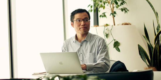 A Deakin business student using a laptop while sitting near a window.