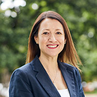 A headshot of Roula Karakostas smiling at the camera.