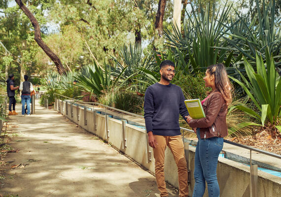 Two students standing on a path on Deakin's Geelong Waurn Ponds campus having a discussion