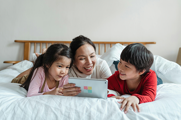 Two children and an adult looking at a digital tablet