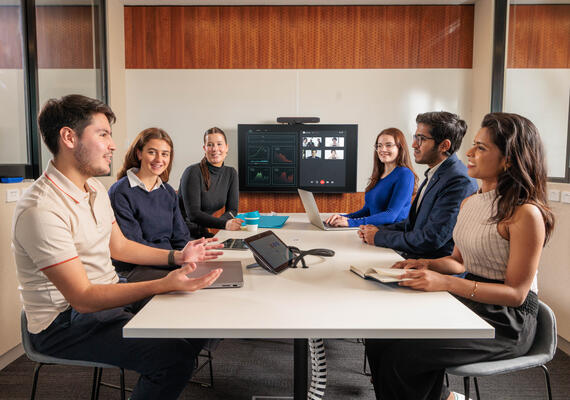 A group of students sit at a table having a discussion.