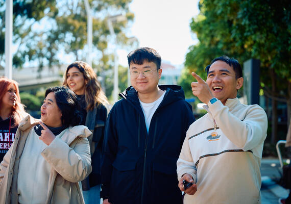 Group of international students walking and laughing together on campus.