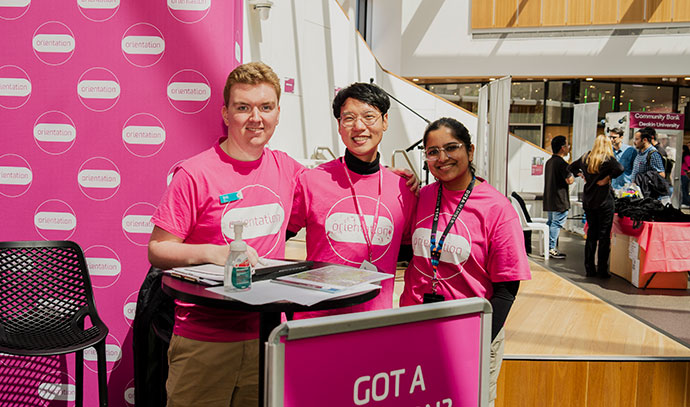 sensoryorientation Three Deakin staff in pink Orientation t-shirts smiling at a welcome desk