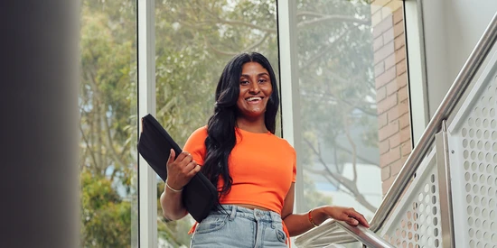 A Deakin transfer student walking down stairs on Burwood campus