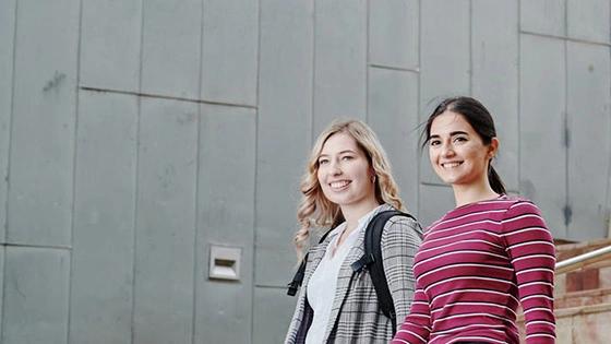 Two Bachelor of Arts and Master of Arts (International Relations) walk down the stairs at Federation Square