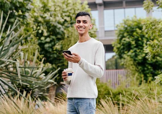 Student smiling holding mobile phone