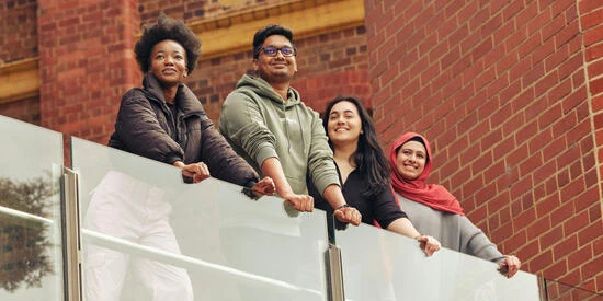 Four students standing on a balcony at the Waterfront campus.