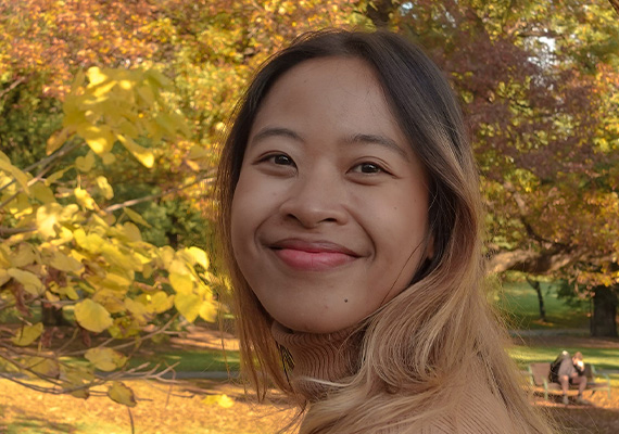 Annisa Laura Maretha smiling in front of trees in autumn.