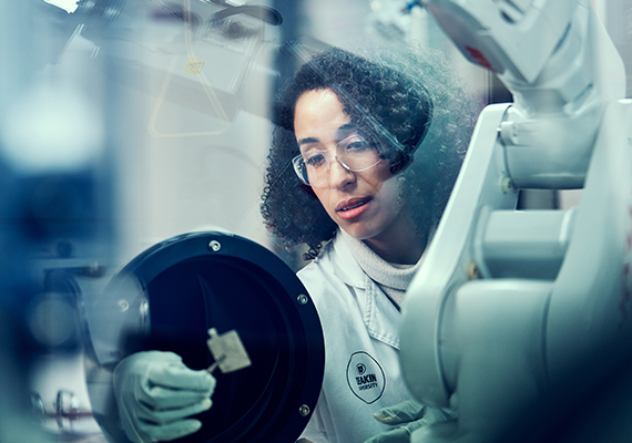 A researcher working in the Deakin University Battery Hub, wearing a lab coat, protective glasses and gloves 