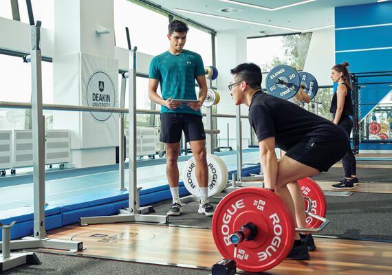 A personal trainer supervises a person lifting weights