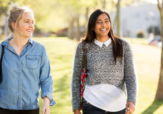 Two people laugh together walking outside.