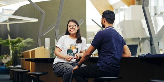 Two students talking at table