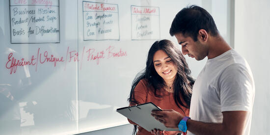 Students discuss content on a whiteboard