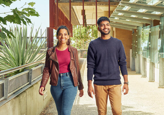 Two Deakin students walking on campus and smiling.