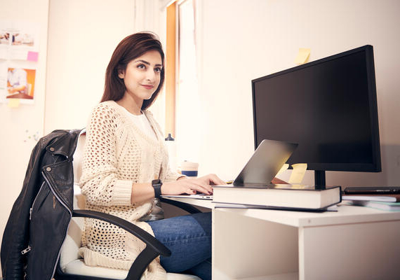 A Deakin student sits at a desk with a computer.