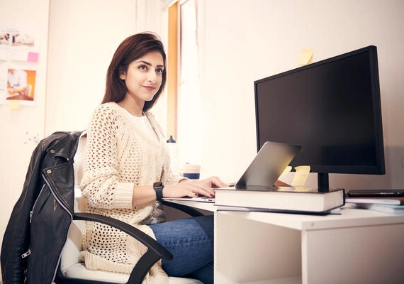 A Deakin student sits at a desk with a computer.