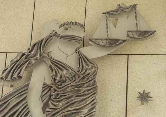 Scales of justice sculpture hangs on the wall. 