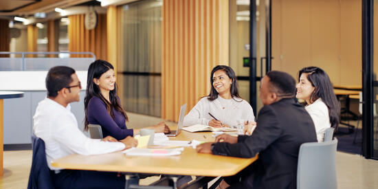 Postgraduate business students sit around a table.