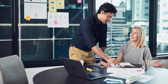 Two students in discussion at a table in an office.