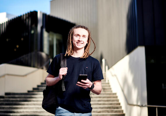 Deakin online student Ben on his phone while walking through campus.