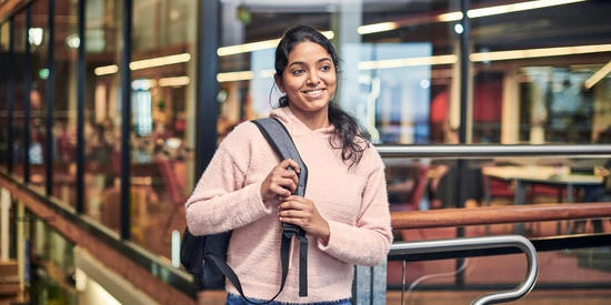 Student smiling while wearing a backpack inside Deakin campus.
