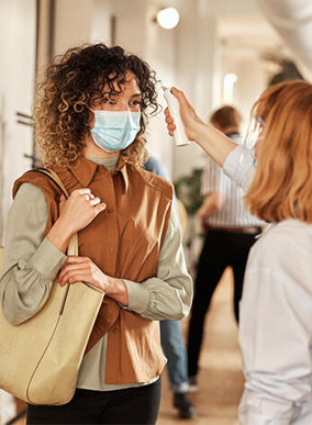 A person has their temperature checked by a hand held device in a medical centre.