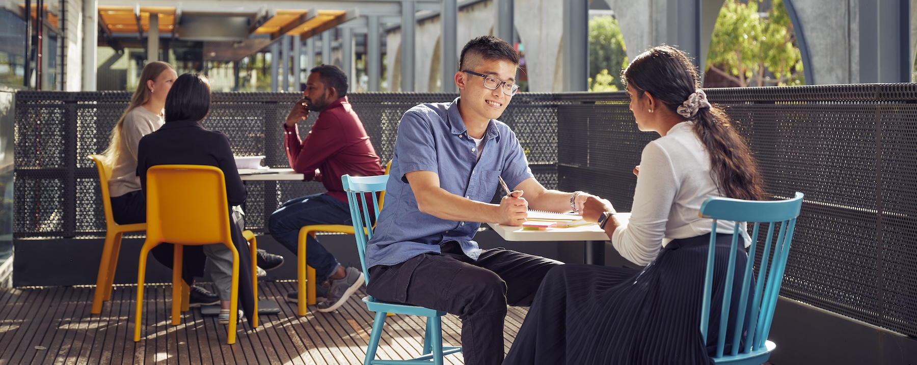 Two students sitting at an outside table, chatting