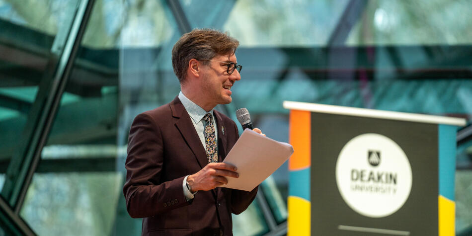 Deakin Doctor Wade Kelly talking on stage with a microphone.