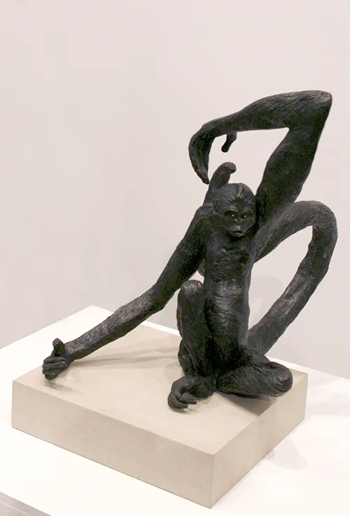 Sculpture of seated black gorilla with long arms and tail