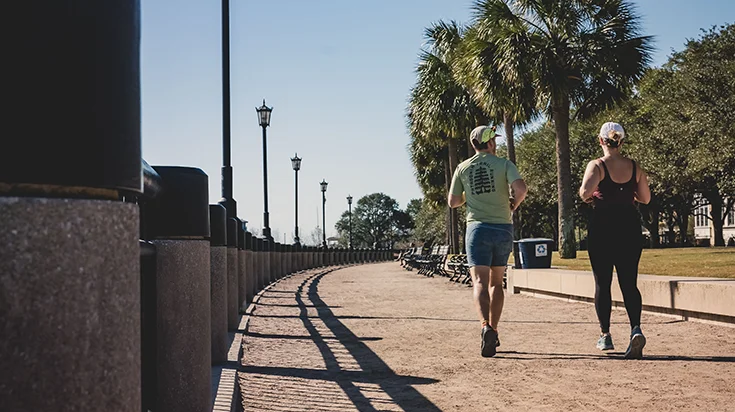 Two people jogging along a path on a sunny day