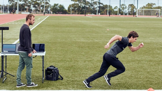 Master of applied sport science students on a field with a setup to test and time a student running.