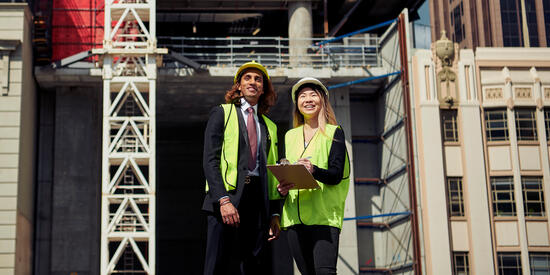Two Deakin construction management students standing near a construction site