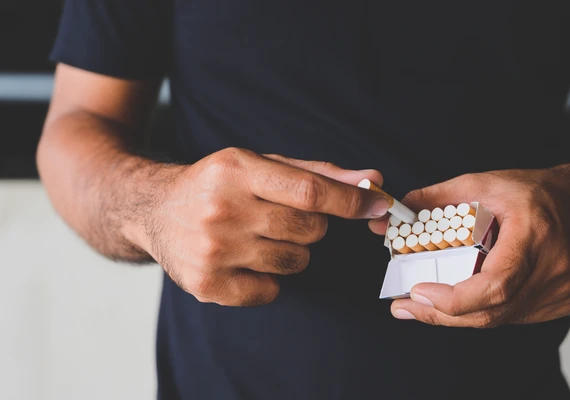 A person opening a packet of cigarettes. 